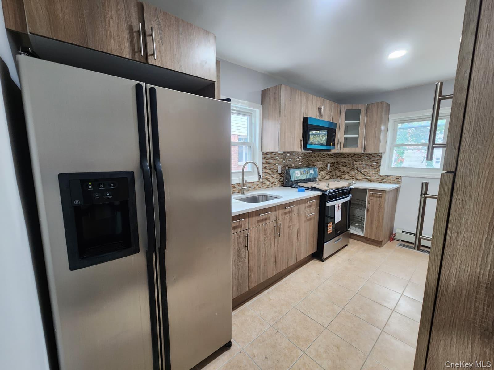 221-26 134th Road Queens, NY 11413 - Photo 9 of 30 a kitchen with stainless steel appliances a refrigerator a sink a stove a microwave and island