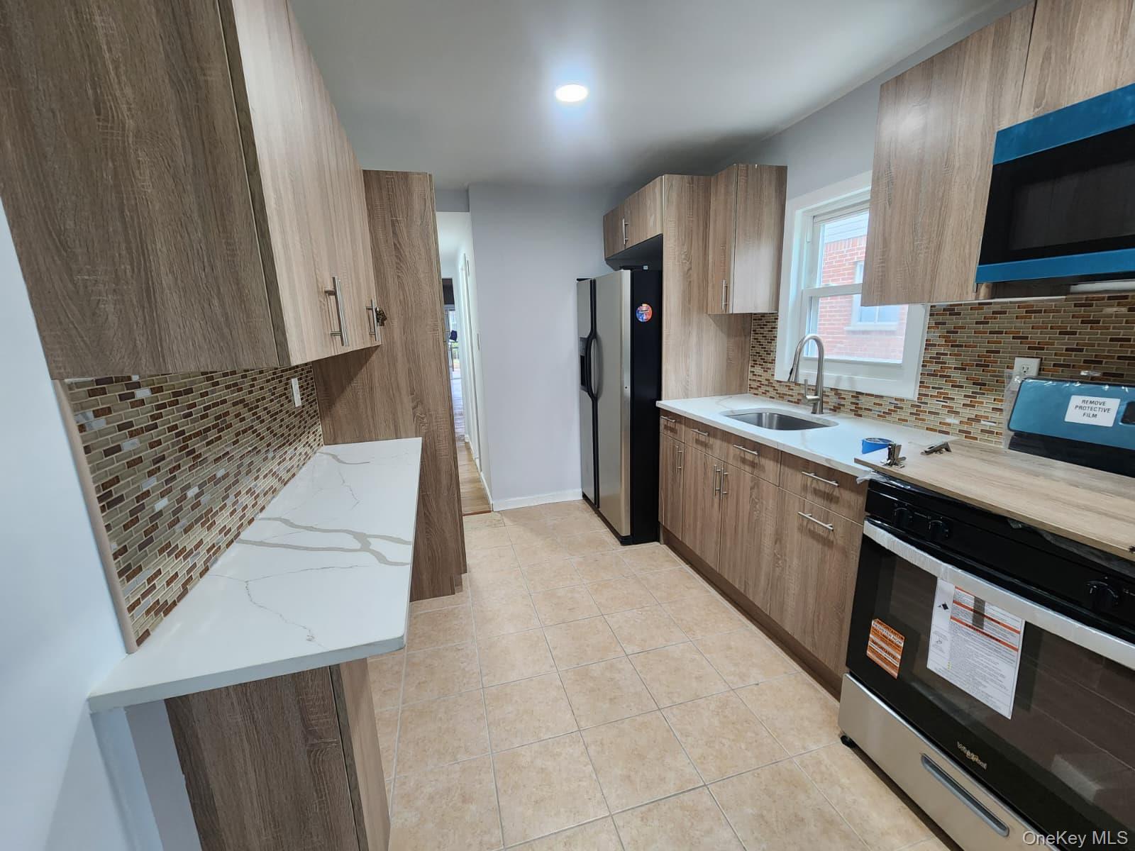 221-26 134th Road Queens, NY 11413 - Photo 10 of 30 a kitchen with stainless steel appliances a stove a sink a refrigerator and cabinets
