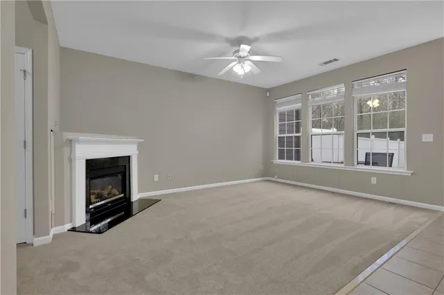 a view of an empty room with chandelier fan and fire place