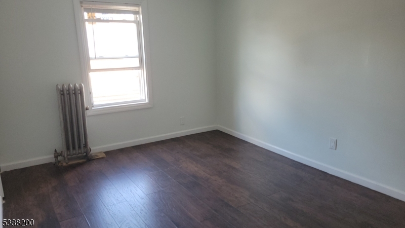 69 Mapes Avenue Newark, NJ 07112 - Photo 5 of 7 an empty room with wooden floor and windows