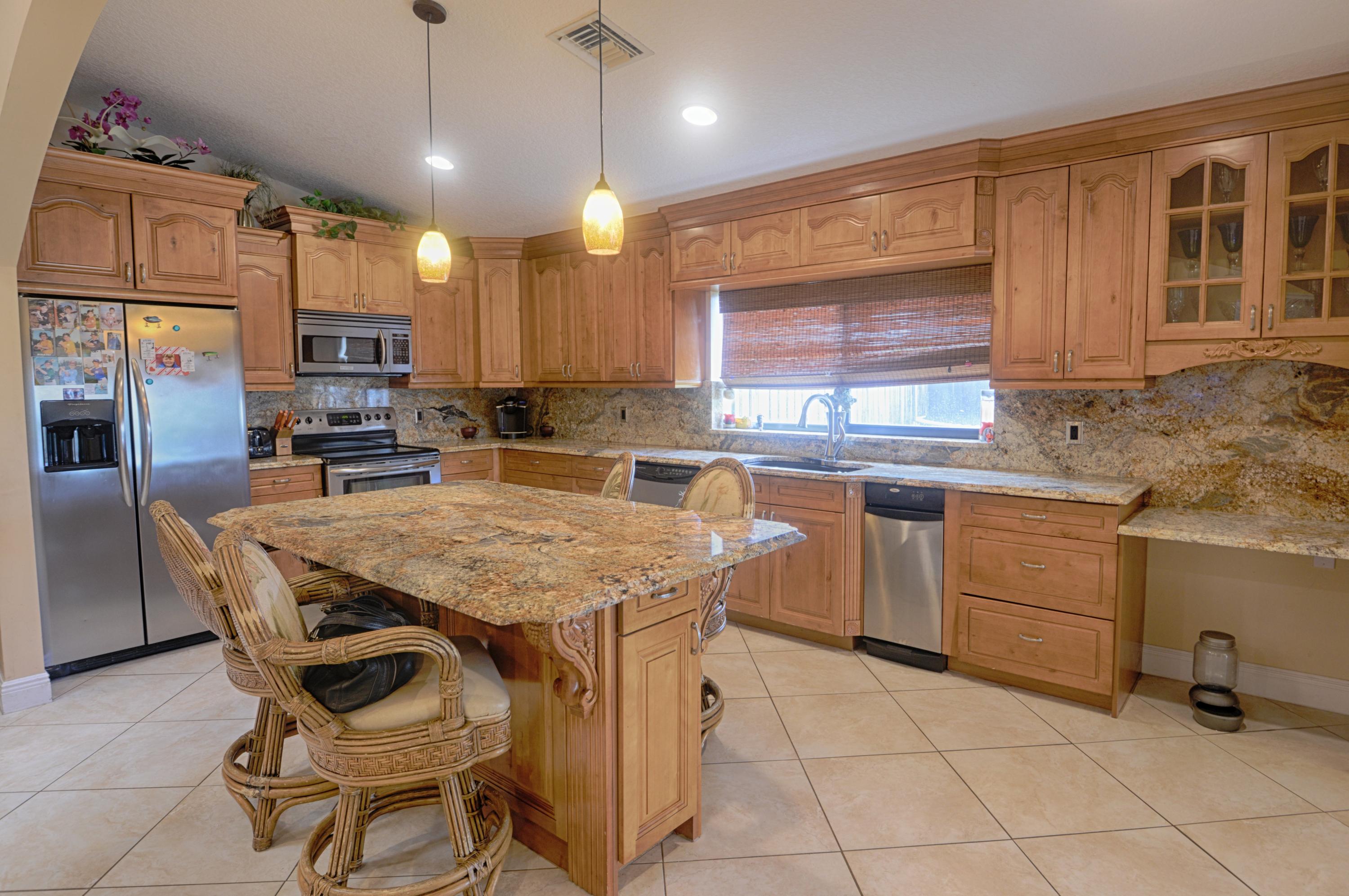 11885 Sunchase Court Boca Raton, FL 33498 - Photo 5 of 25 a kitchen with a stove a sink dishwasher a refrigerator and wooden cabinets with wooden floor