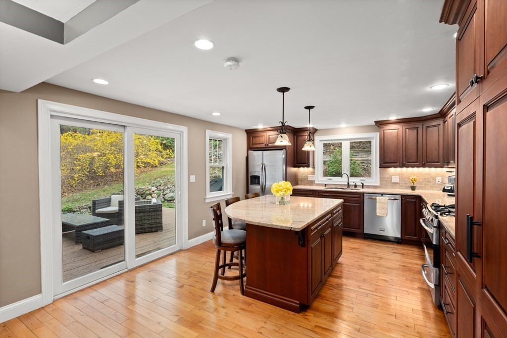 a kitchen with kitchen island granite countertop wooden floors and a view of living room