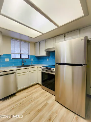 a kitchen with granite countertop a refrigerator stove top oven and sink