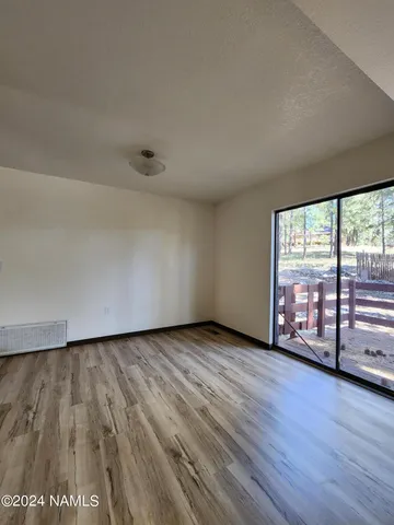 a view of an empty room with wooden floor and fence