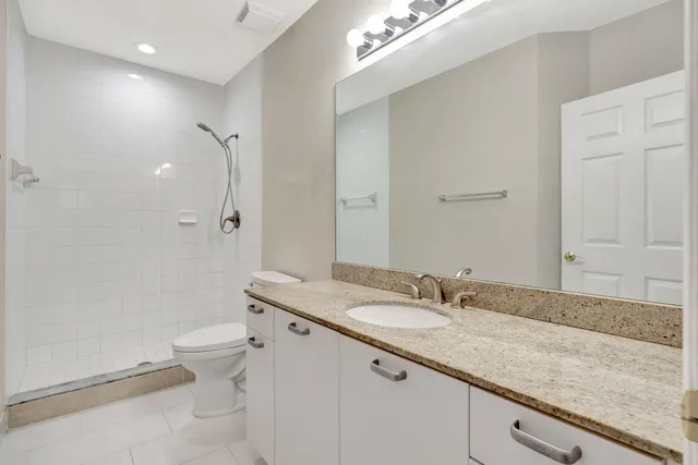 a bathroom with a granite countertop sink a toilet and shower
