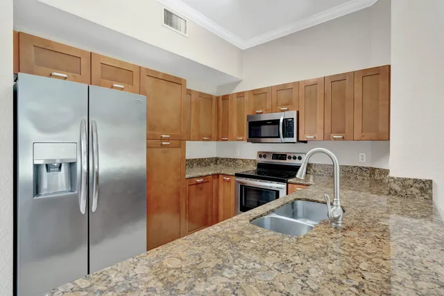 a kitchen with granite countertop a refrigerator stove and microwave