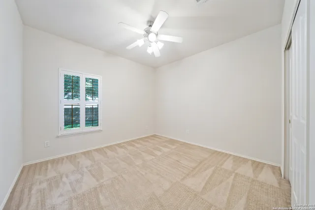an empty room with windows and ceiling fan