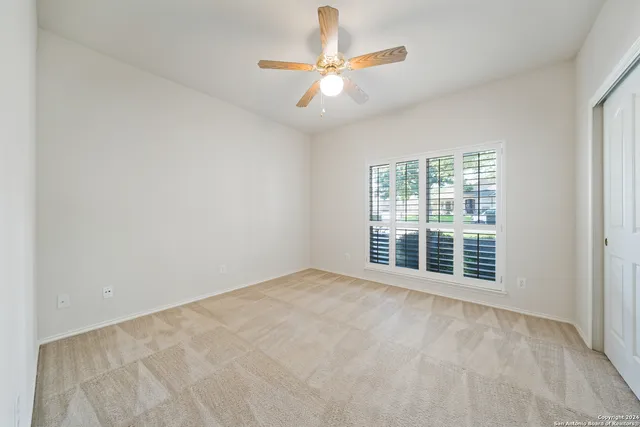 an empty room with a ceiling fan and window