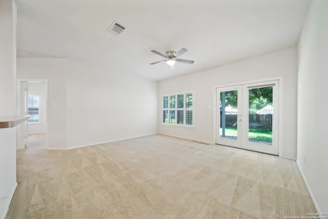 an empty room with windows and ceiling fan