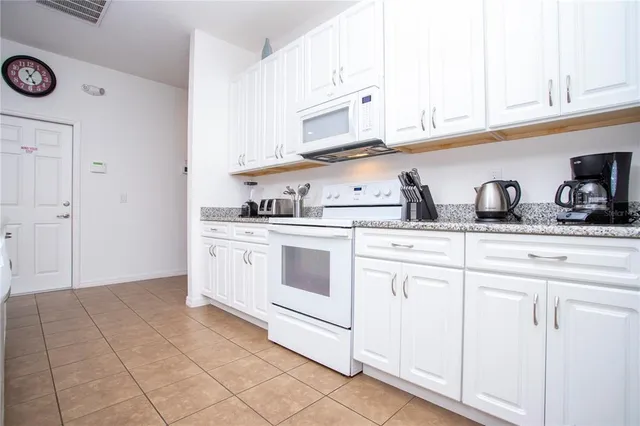 a kitchen with white cabinets and white appliances