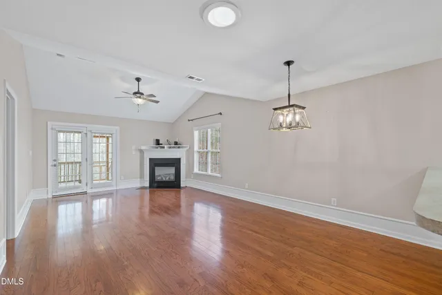 a view of a room with wooden floor fireplace and windows