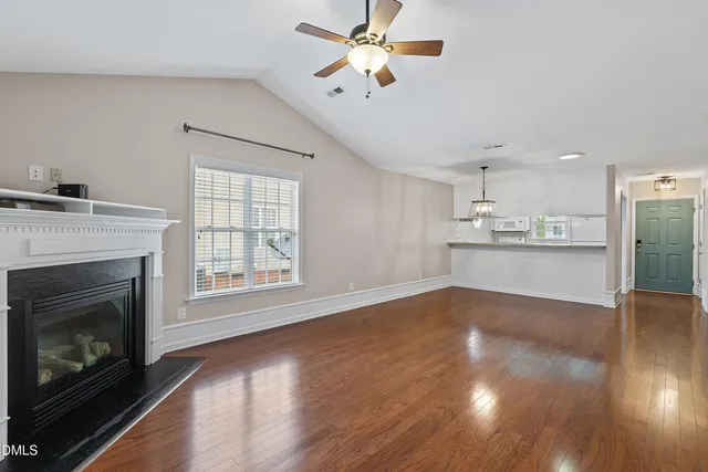 a view of an empty room with wooden floor and a fireplace