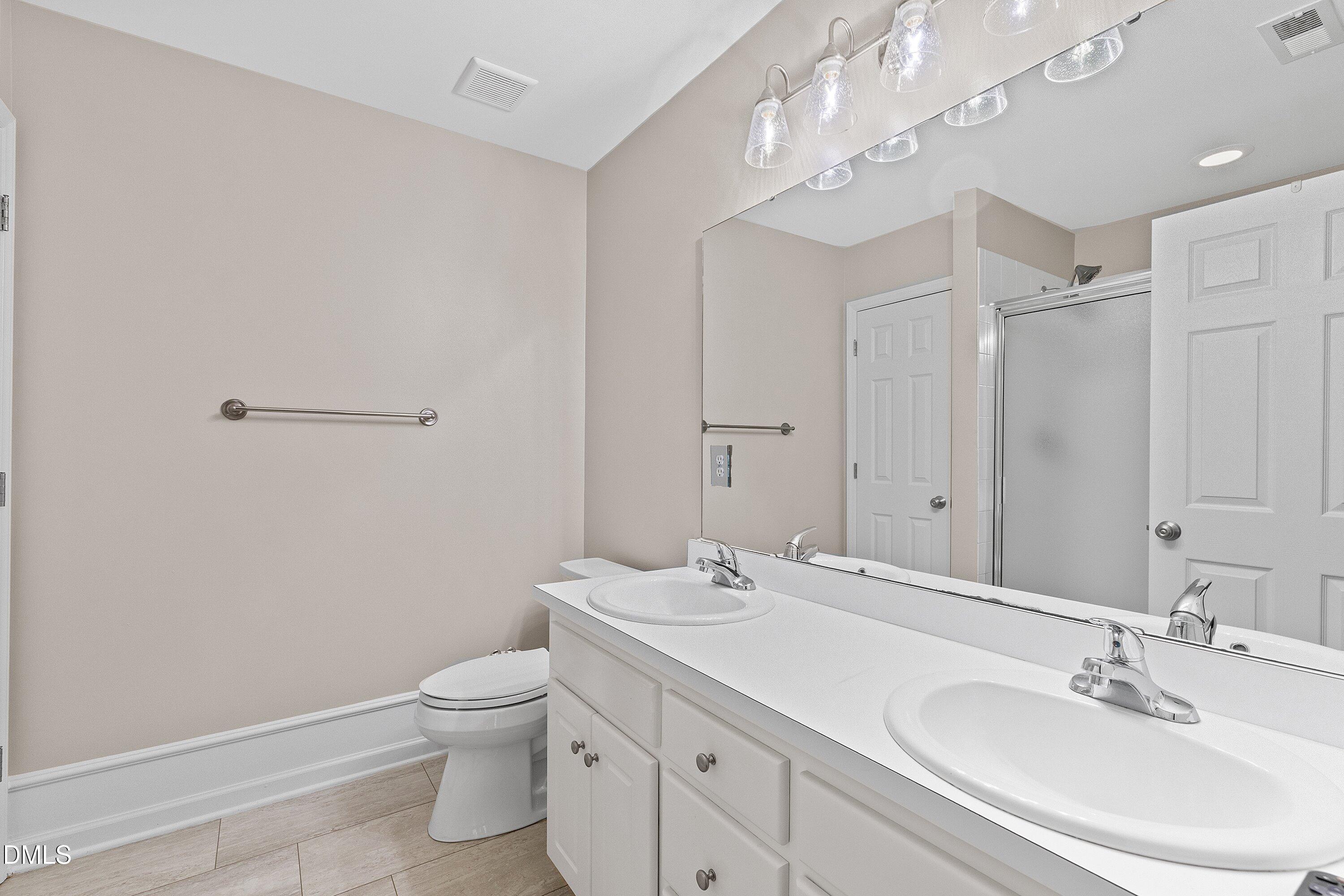3666 East Cotton Gin Drive Clayton, NC 27527 - Photo 24 of 33 a bathroom with a toilet a sink a mirror and a shower