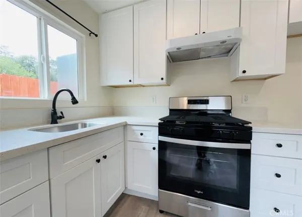 a kitchen with stainless steel appliances granite countertop white cabinets and a stove
