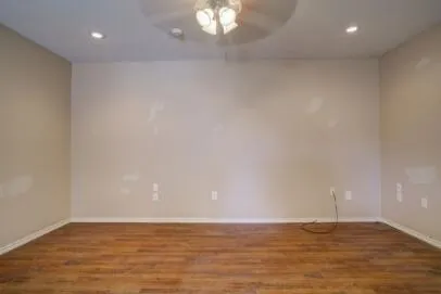 a view of an empty room with window and wooden floor