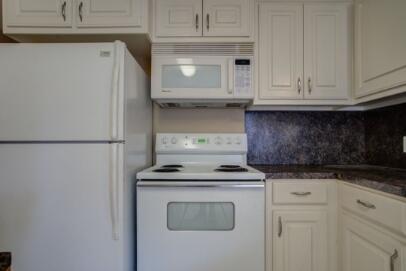 2601 33rd Street, Unit REAR Lubbock, TX 79410 - Photo 8 of 16 a kitchen with granite countertop white cabinets and white appliances