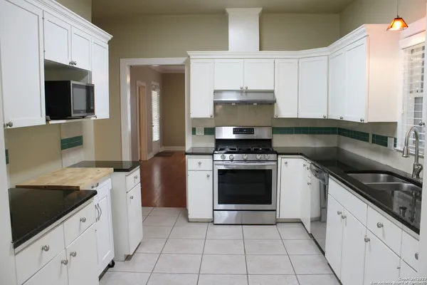 a kitchen with granite countertop a stove sink and cabinets