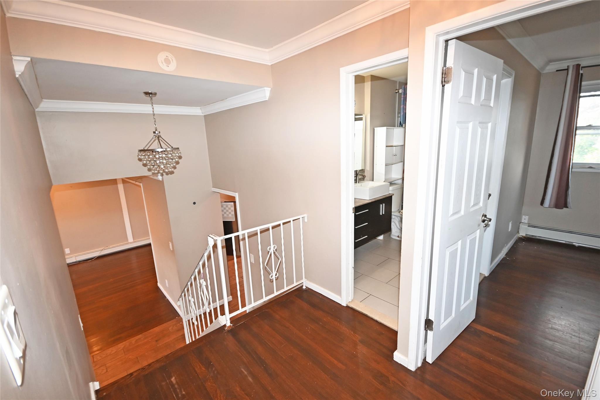 89 Osborne Road West Hempstead, NY 11552 - Photo 17 of 50 Hallway with an upstairs landing, ornamental molding, dark wood-style floors, a chandelier, and a baseboard heating unit