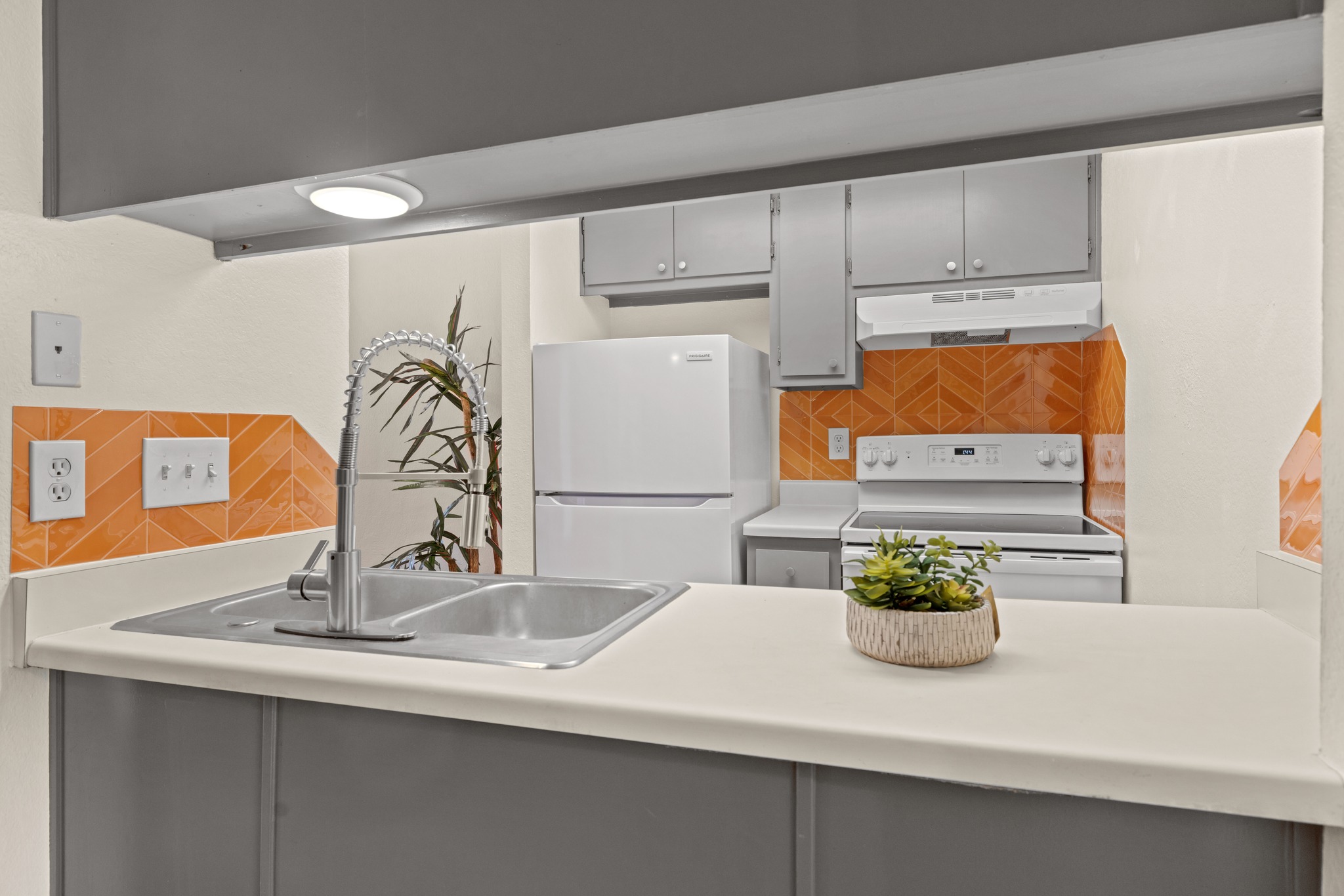 9079 Jollyville Road, Unit 301 Austin, TX 78759 - Photo 29 of 38 #203 A compact kitchen offers a stainless steel sink and modern appliances against an orange tiled backsplash.