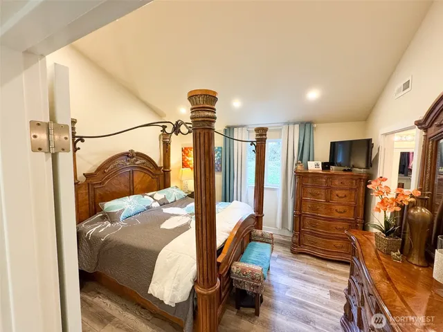 a bedroom with furniture a flat screen tv and a refrigerator