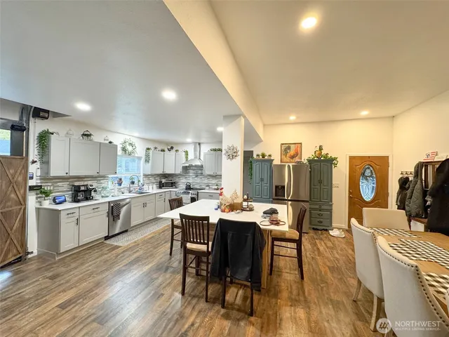 a kitchen with stainless steel appliances kitchen island granite countertop a dining table chairs stove a refrigerator and cabinets