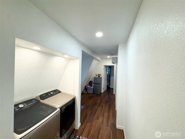 a view of a hallway with wooden floor and a bathroom