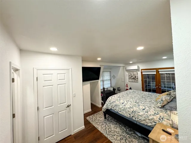 a bedroom with a large bed a flat tv screen and dresser