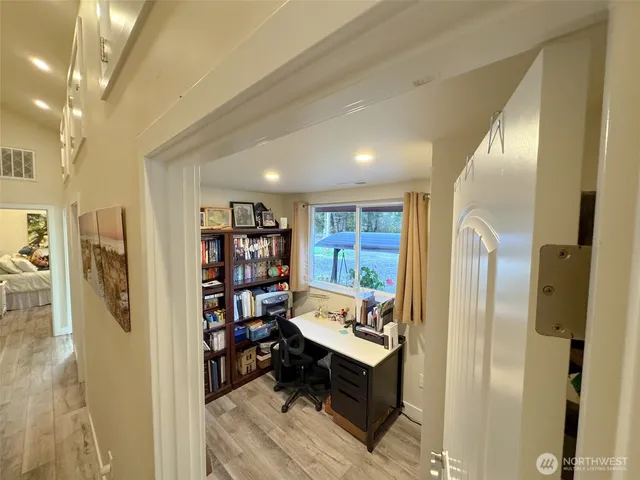 a living room with stainless steel appliances furniture a rug and a bookshelf