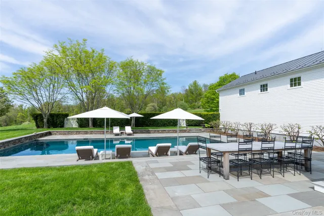 a view of a swimming pool with chairs and table under an umbrella