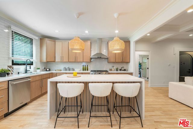 a large kitchen with kitchen island granite countertop wooden floor white cabinets and stainless steel appliances