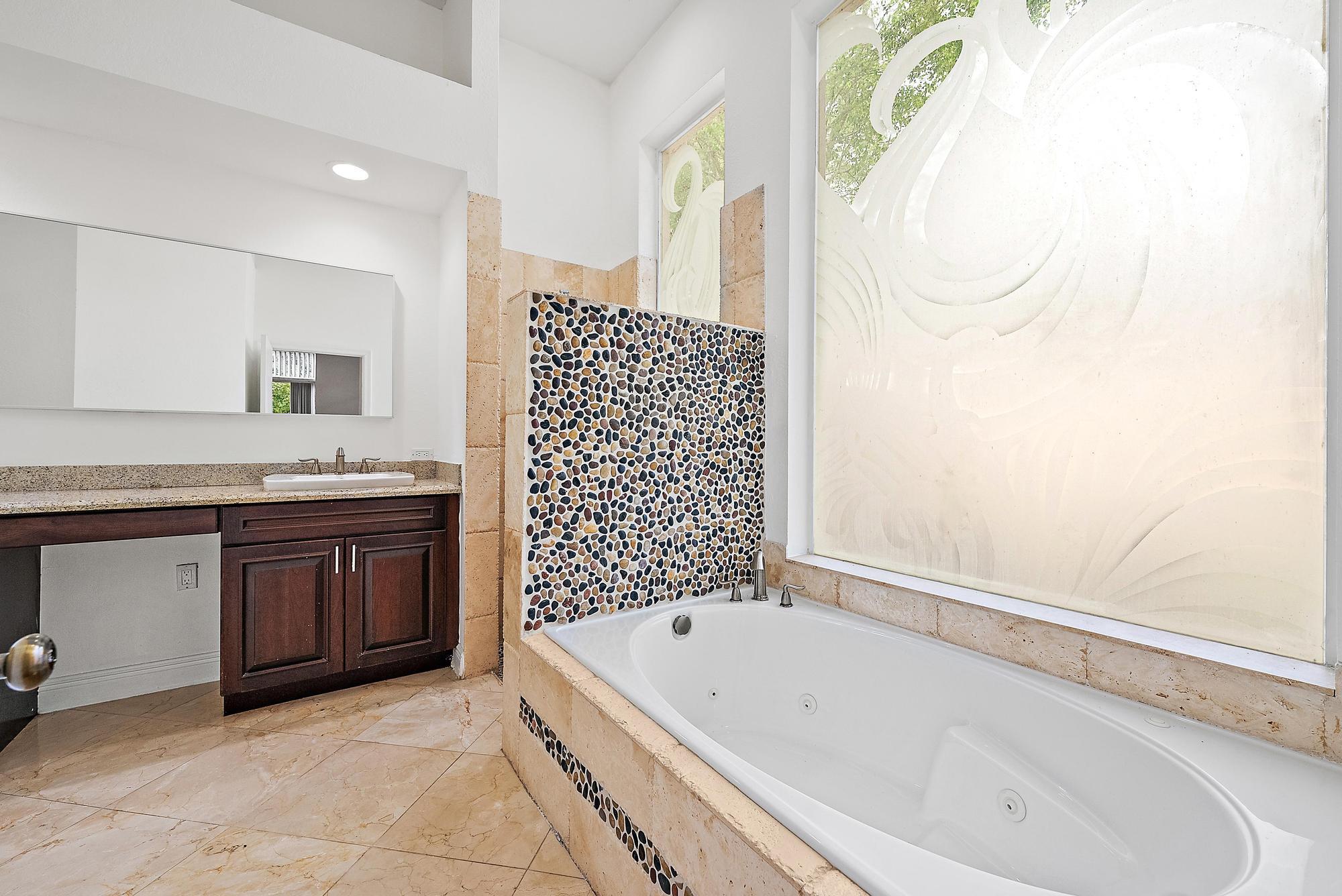 6612 Northwest 23rd Terrace Boca Raton, FL 33496 - Photo 13 of 20 a bathroom with a granite countertop bathtub sink vanity and mirror