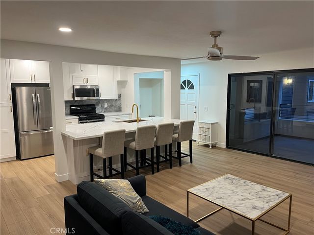 a living room with stainless steel appliances furniture and wooden floor