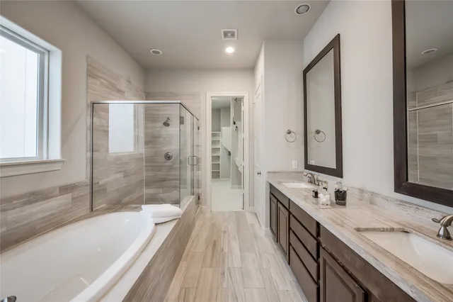 a spacious bathroom with a granite countertop tub sink a mirror a shower and vanity