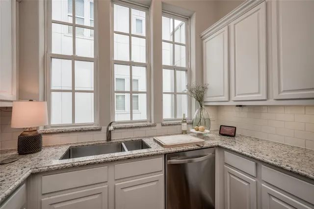 a kitchen with granite countertop white cabinets and stainless steel appliances