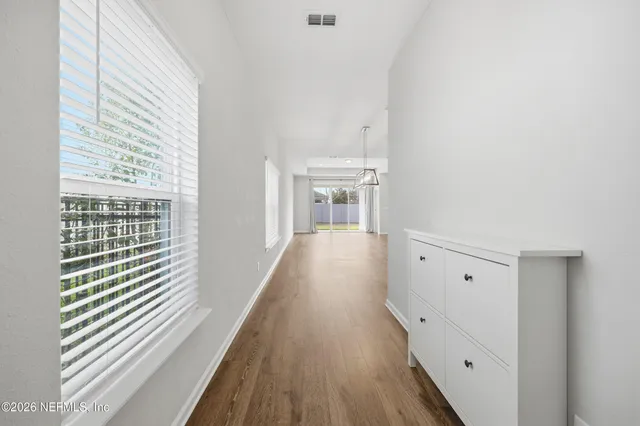 a view of a hallway with wooden floor and a bathroom
