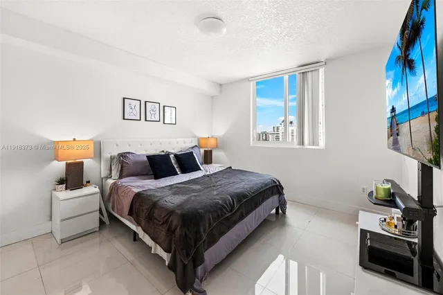 a bedroom with a bed lamp and a potted plant on the dresser