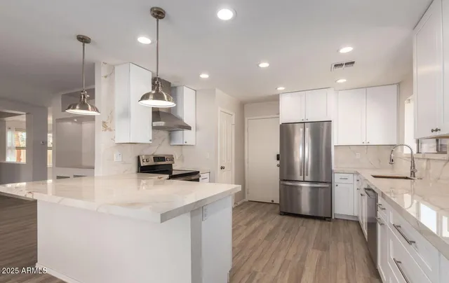 a kitchen with stainless steel appliances a refrigerator sink and wooden floor