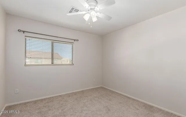 an empty room with a window and a fan