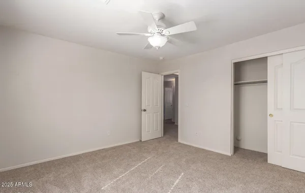 an empty room with closet and ceiling fan