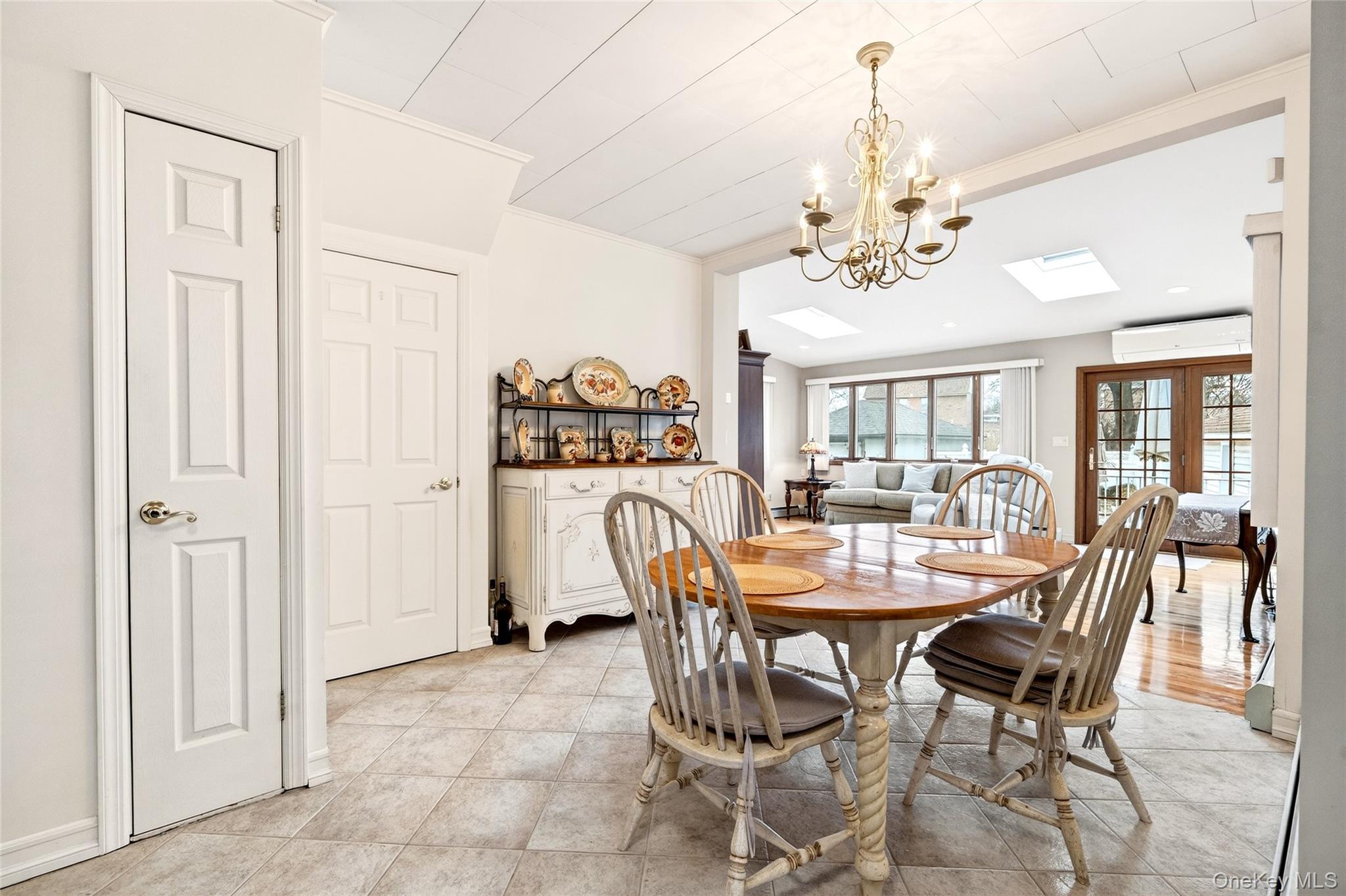 3334 Country Club Road Bronx, NY 10465 - Photo 15 of 49 Dining room with crown molding, a chandelier, french doors, light tile patterned floors, and a skylight