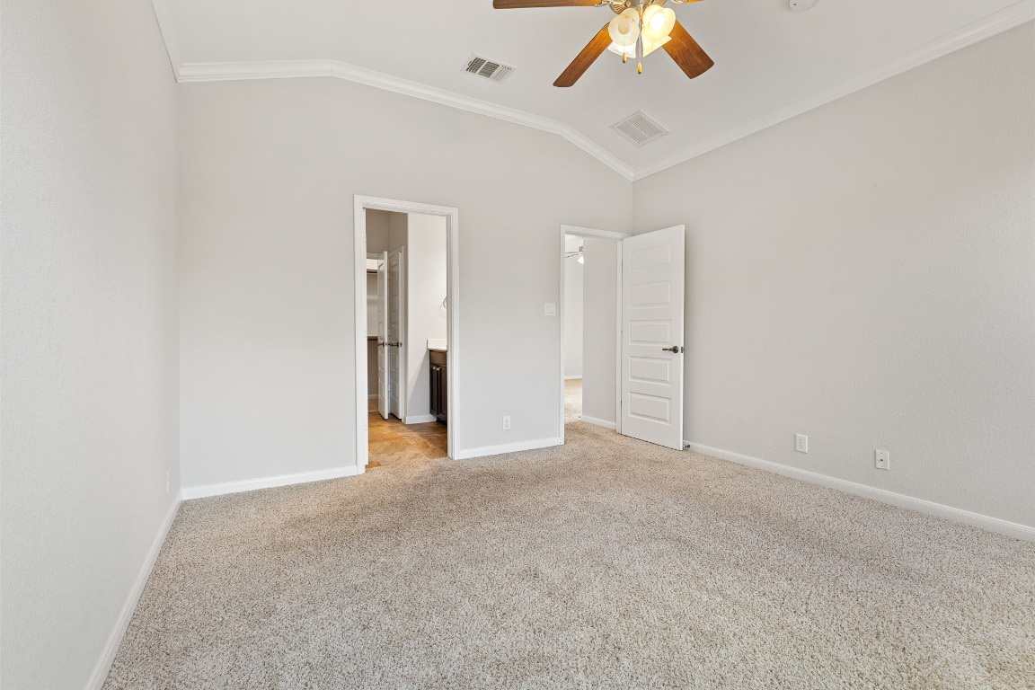 506 Hummingbird Lane, Unit A Austin, TX 78734 - Photo 25 of 36 Unfurnished bedroom featuring lofted ceiling, ornamental molding, carpet, connected bathroom, and ceiling fan
