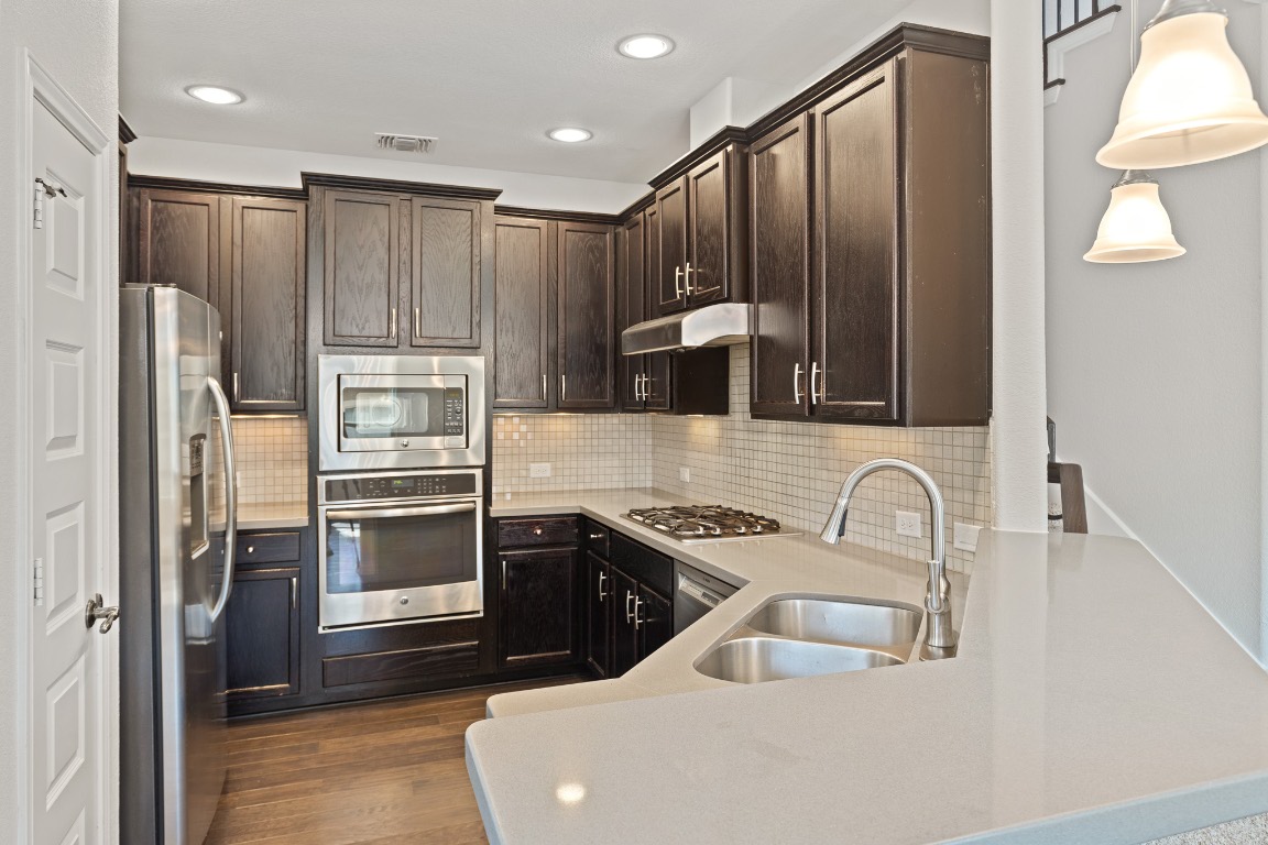 506 Hummingbird Lane, Unit A Austin, TX 78734 - Photo 3 of 36 Kitchen featuring stainless steel appliances, dark brown cabinets, backsplash, recessed lighting, and dark wood-type flooring
