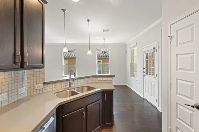 an empty room with wooden floor cabinet and windows