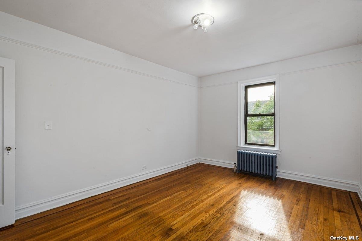 83-10 35th Avenue, Unit 5L Queens, NY 11372 - Photo 11 of 17 an empty room with wooden floor and windows