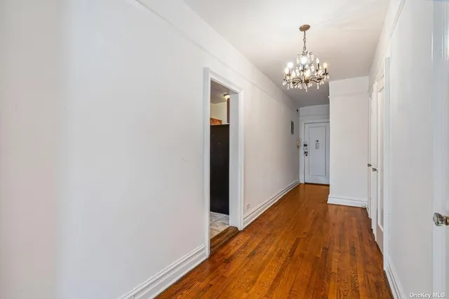 a view of a hallway with wooden floor and a chandelier