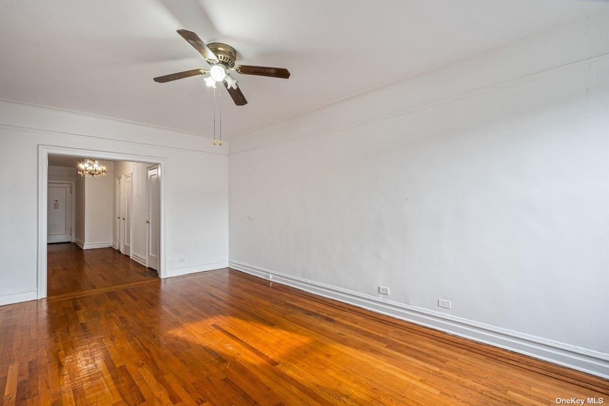 83-10 35th Avenue, Unit 5L Queens, NY 11372 - Photo 7 of 17 an empty room with wooden floor fan and windows