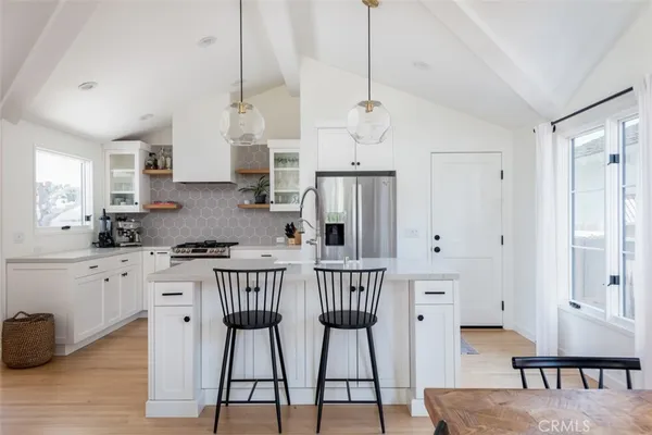 a kitchen with stainless steel appliances granite countertop a refrigerator a stove a sink dishwasher and white cabinets with wooden floor