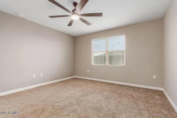 an empty room with windows and ceiling fan