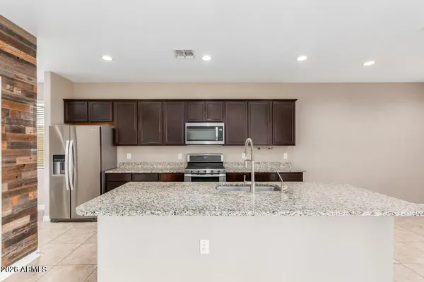 a kitchen with stainless steel appliances kitchen island granite countertop a refrigerator and a stove top oven