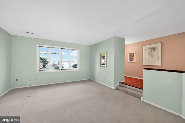 an empty room with painting on the wall and a window